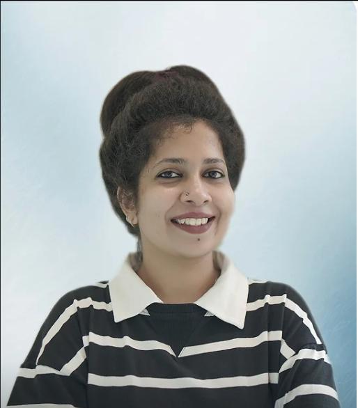 Professional headshot of Vidya Parakat, Entrepreneur, smiling brightly and wearing a black and white striped shirt with a collar, against a soft blue background.